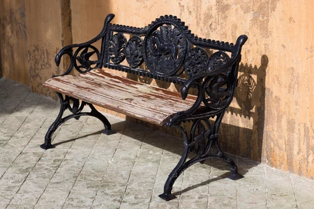 Ornate Iron Bench Against Stucco Wall
