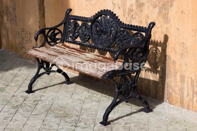 Ornate Iron Bench Against Stucco Wall
