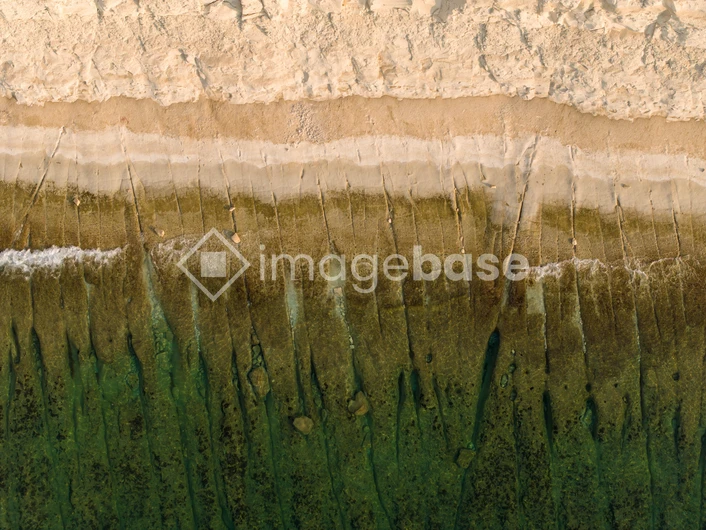 Aerial View of Sandy Beach and Green Waters