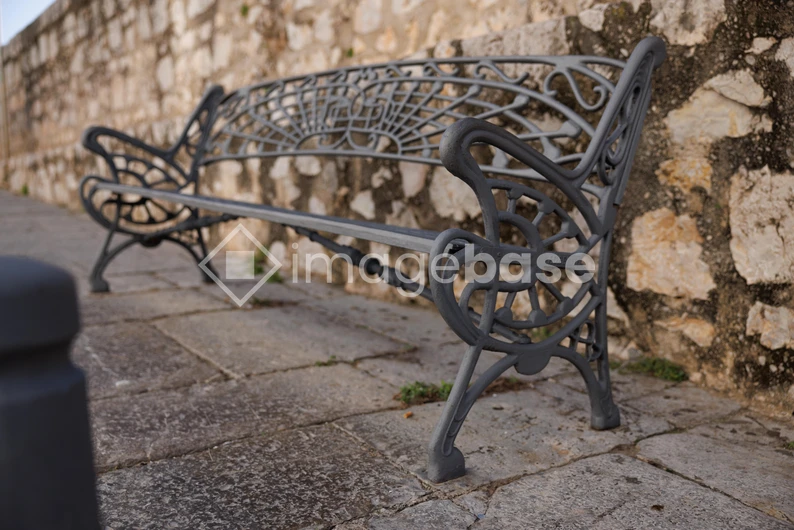 Ornate Park Bench by Stone Wall